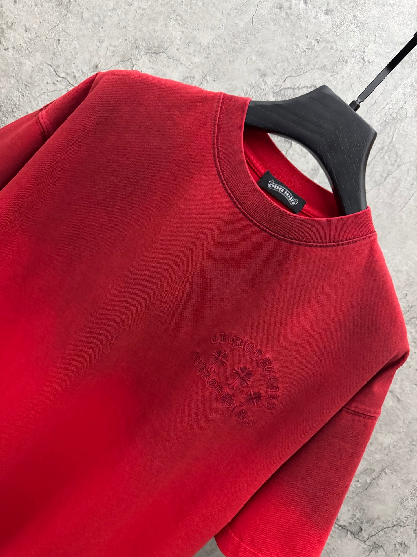 Red T-shirt neckline and shoulder with small rhinestone logo detail