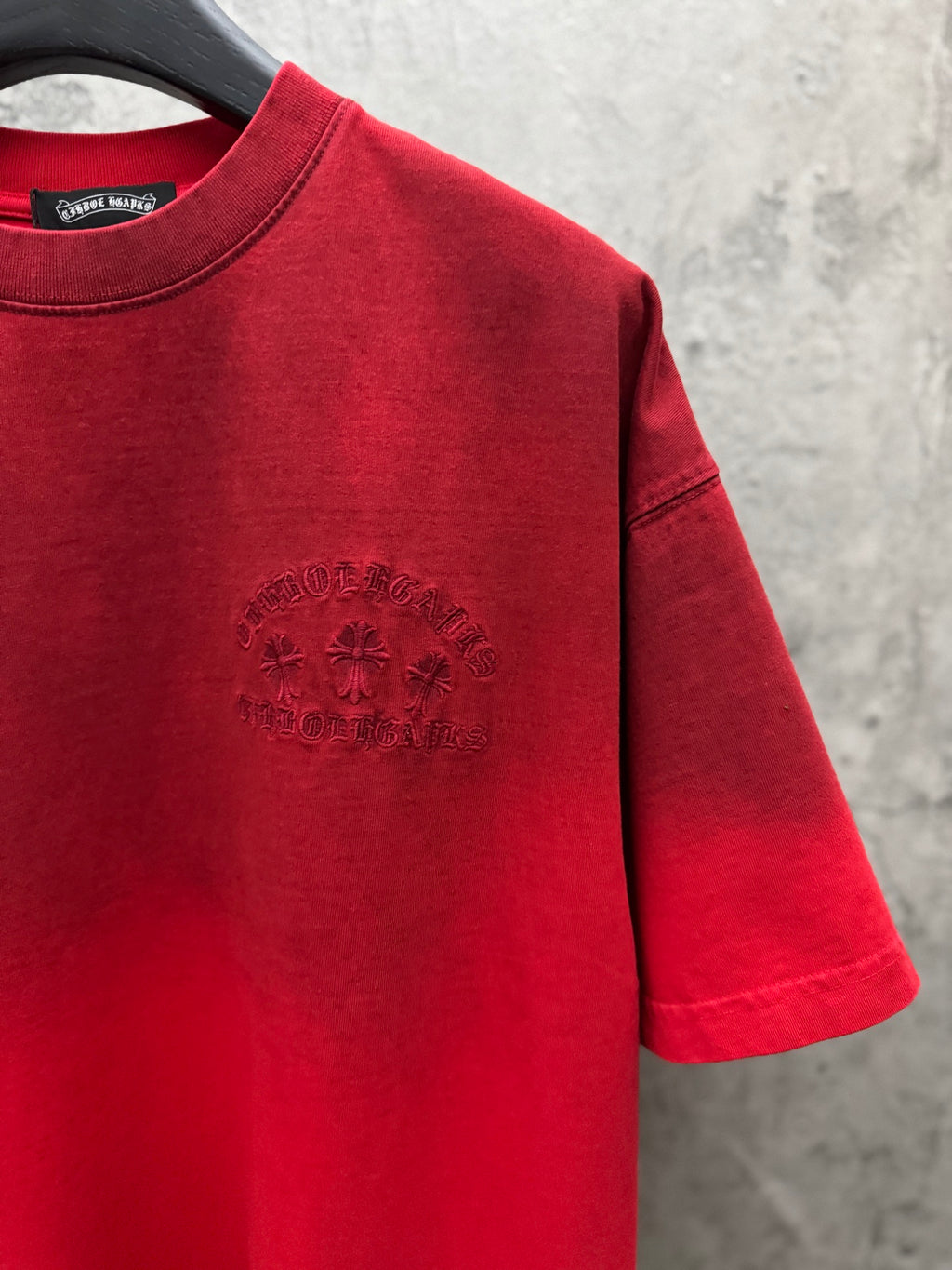 Red T-shirt front with small centered emblem, short sleeves, and crew neck