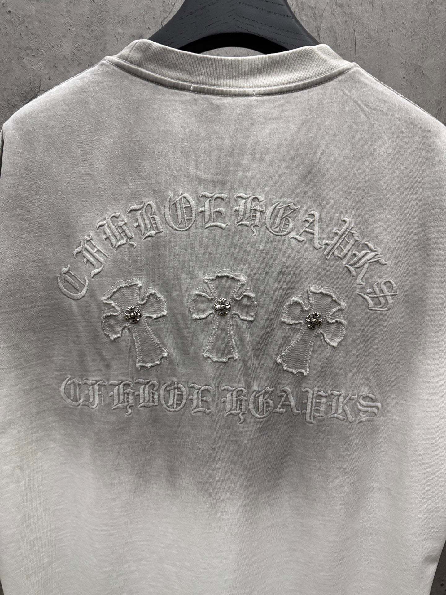 Light gray short-sleeve T-shirt back view with embroidered crest, crosses, and text