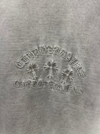 Light gray T-shirt chest embroidery close-up with floral cross and arched lettering