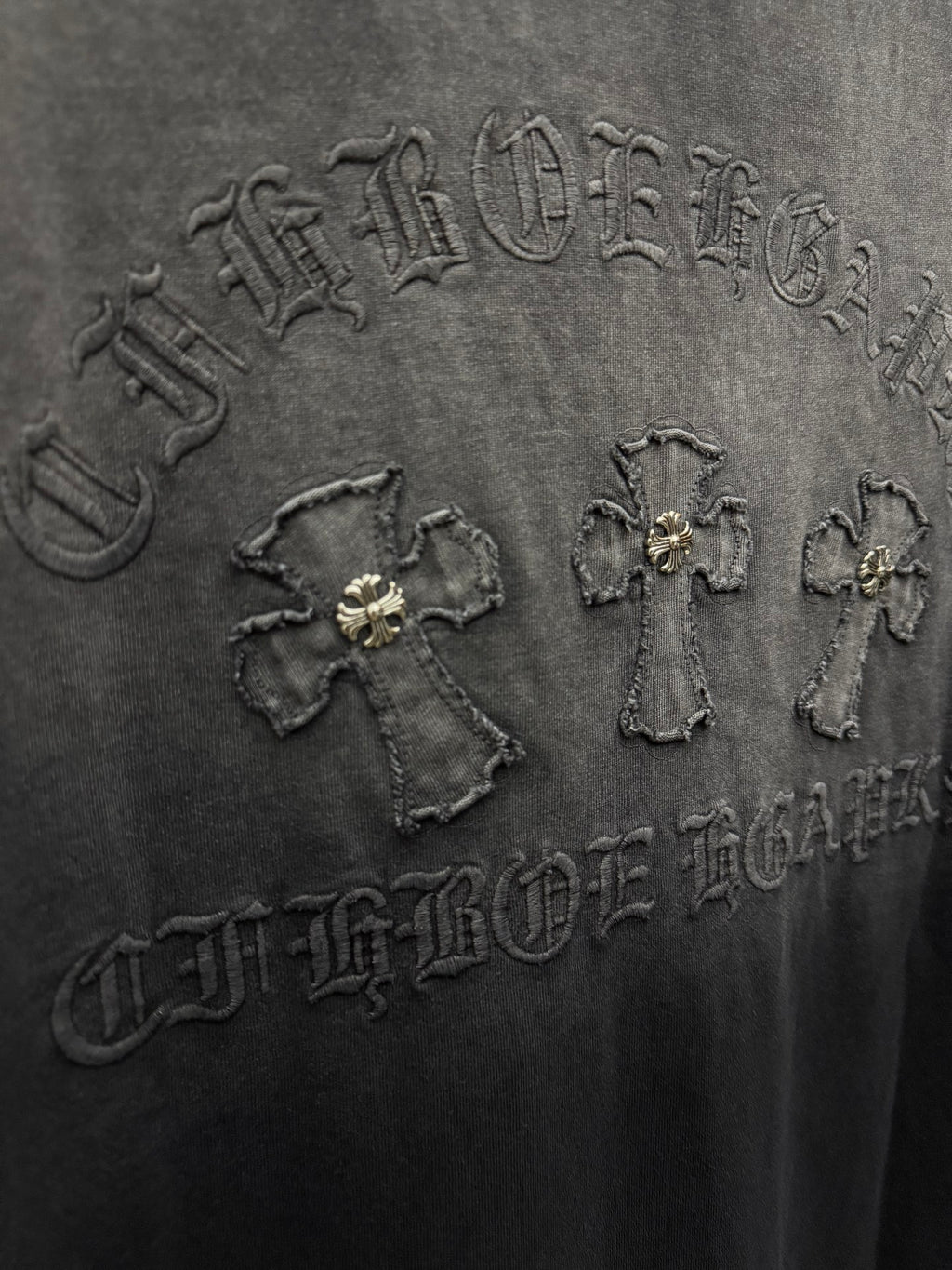 Dark gray T-shirt close-up of raised back graphic with small emblems