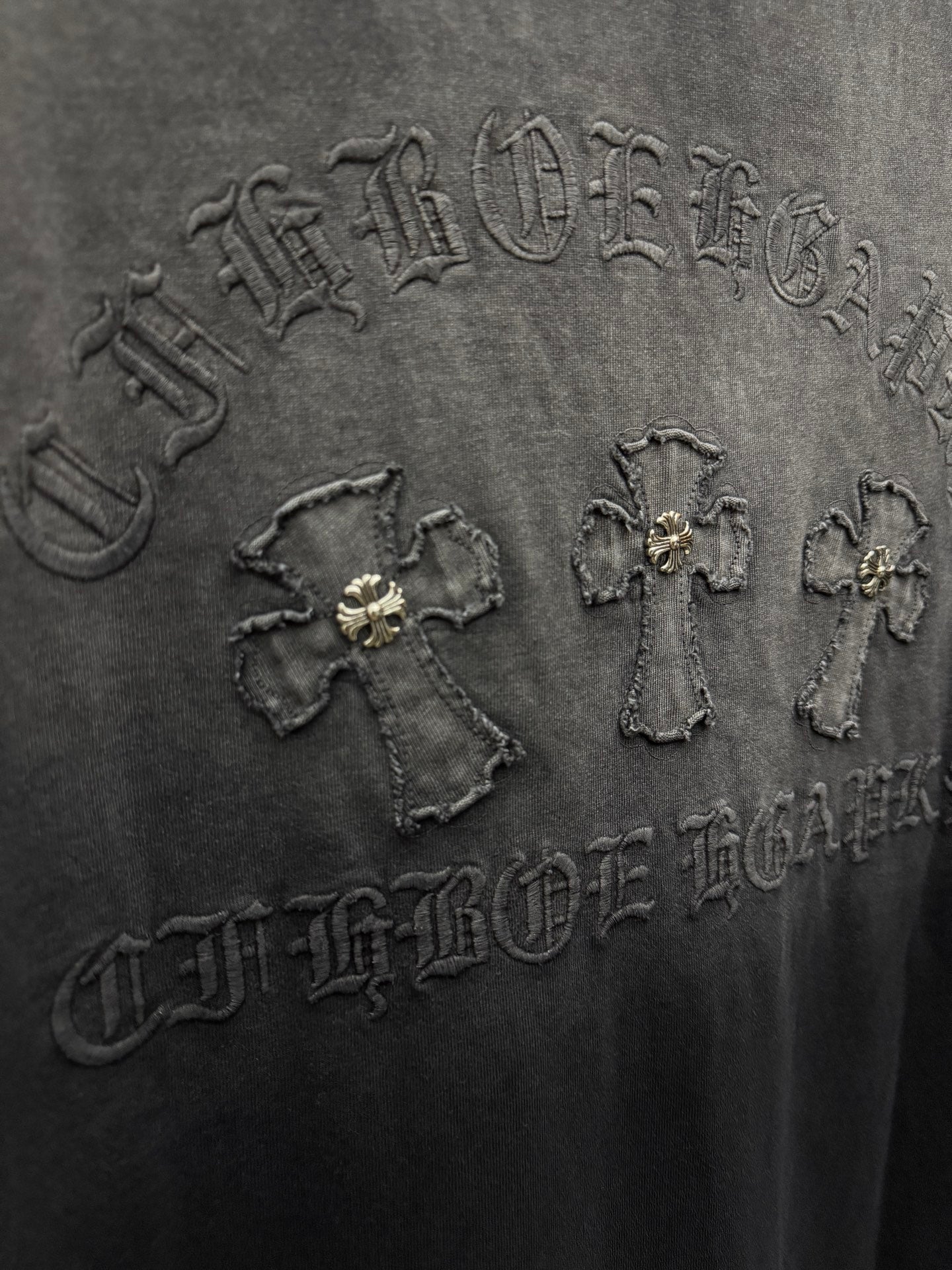 Dark gray T-shirt close-up of raised back graphic with small emblems