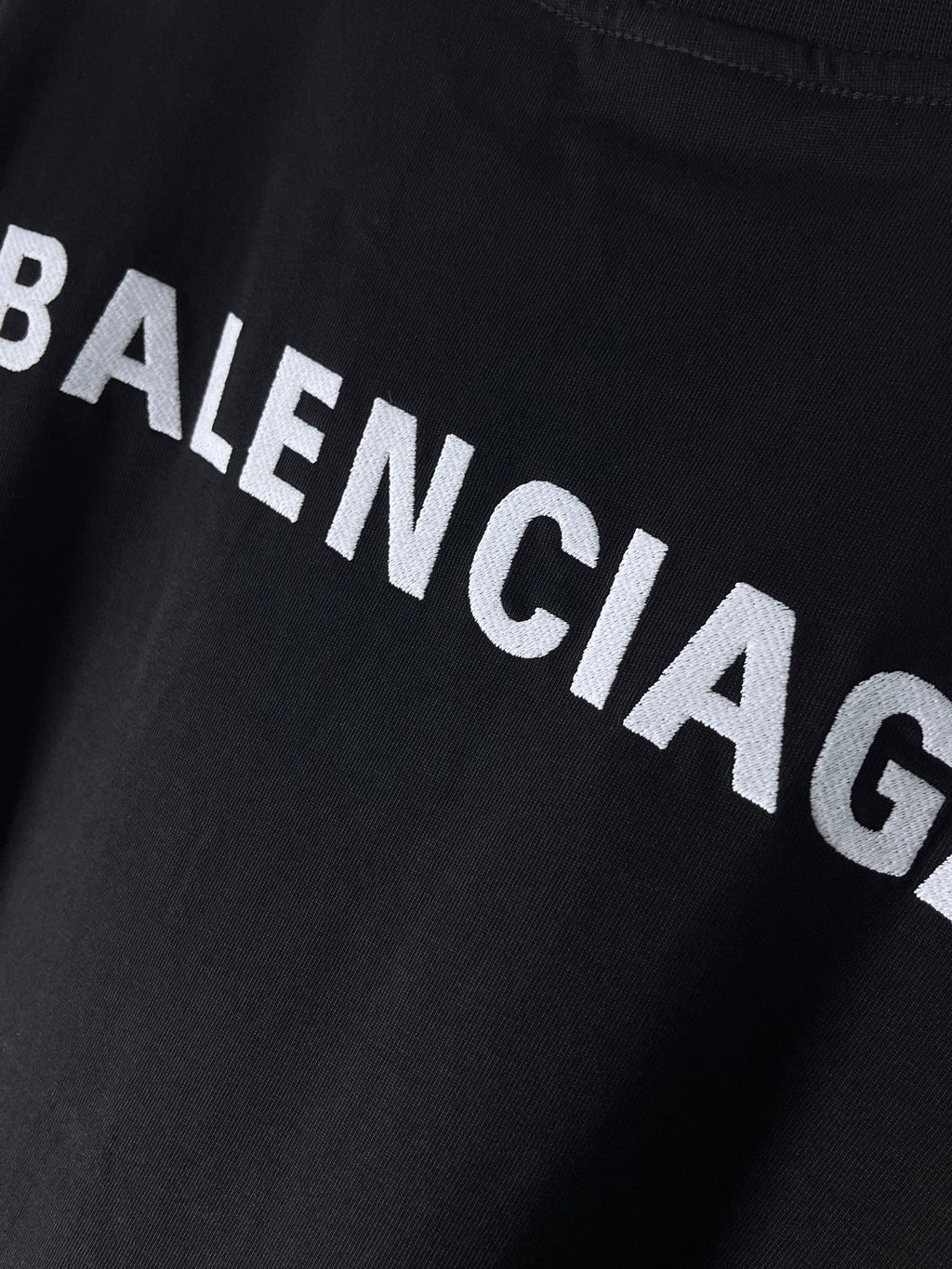 Balenciaga text logo on dark navy T-shirt, close-up of lettering