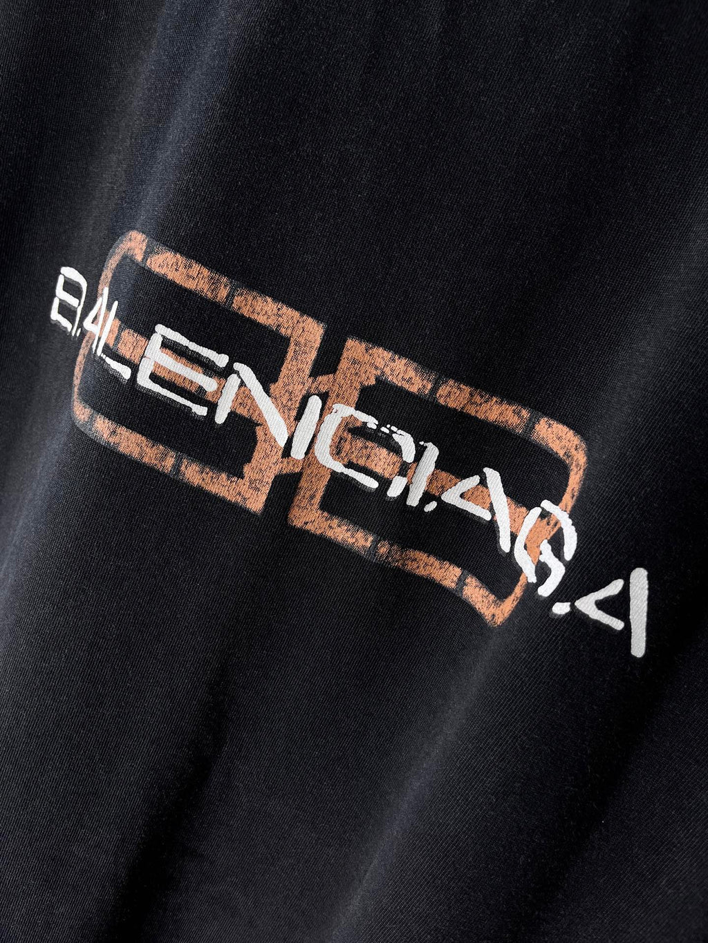 Balenciaga T-shirt, dark color, close-up of distressed front Balenciaga logo
