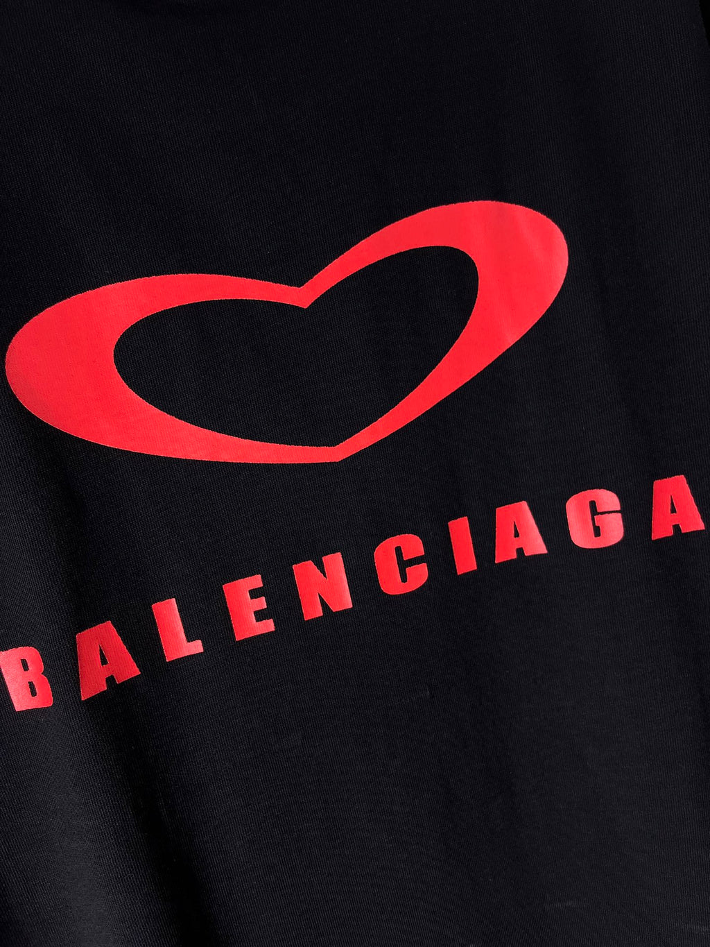 Black T-shirt close-up with large red heart and Balenciaga logo text
