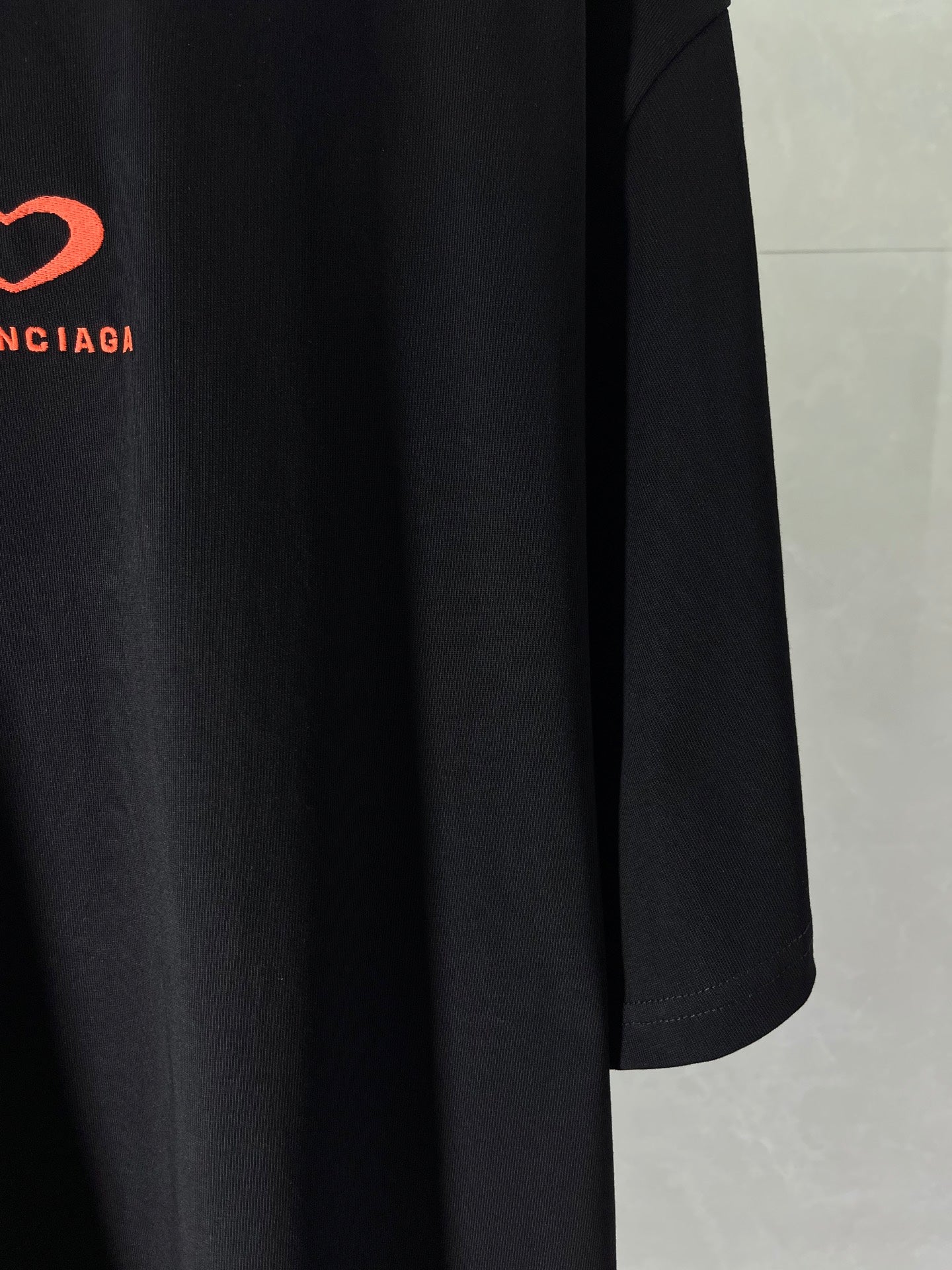 Black T-shirt lower front view with draped fabric and straight hem