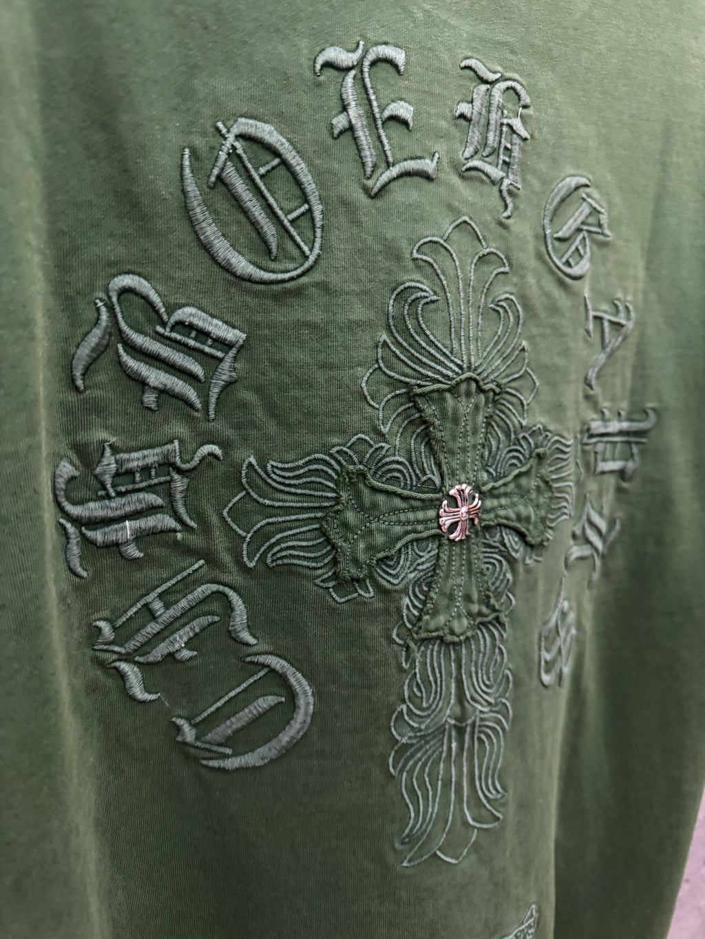 Green T-shirt close-up of large back embroidered emblem and cross