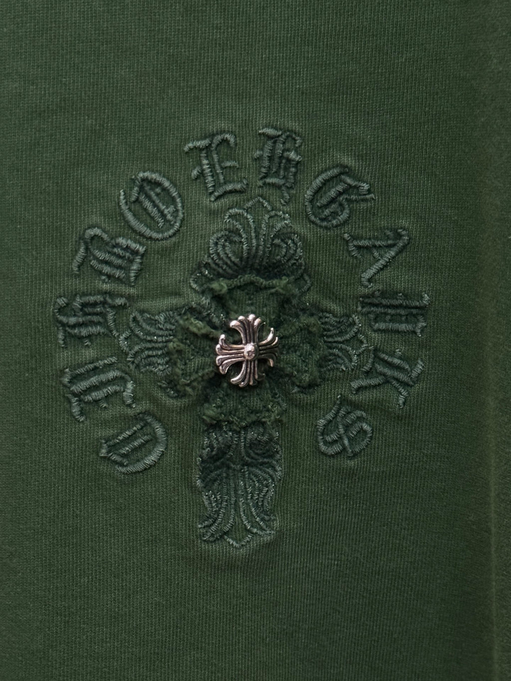 Green T-shirt fabric with detailed small embroidered cross logo