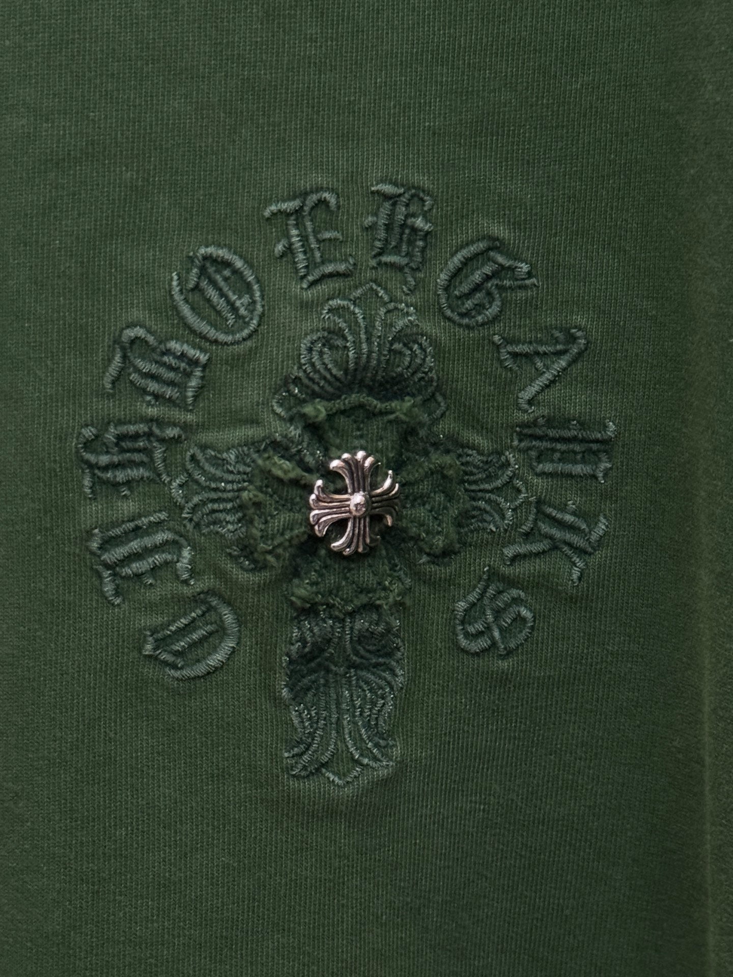 Green T-shirt fabric with detailed small embroidered cross logo