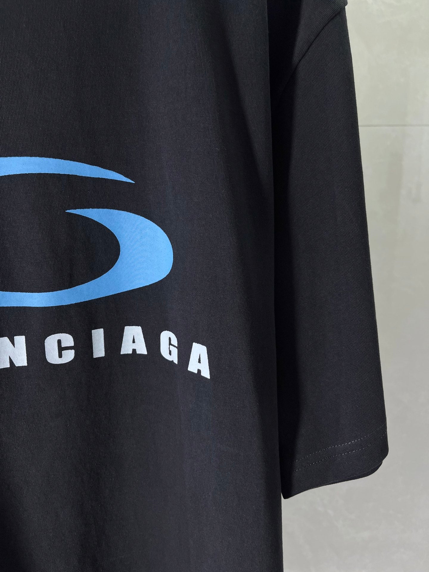 Balenciaga dark T-shirt sleeve with blue logo and BALENCIAGA lettering