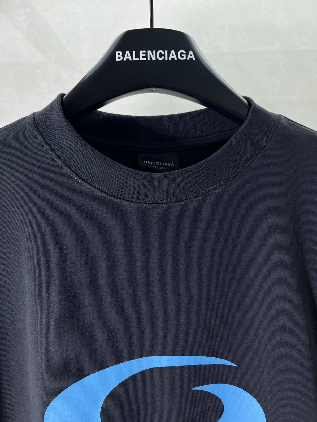 Balenciaga dark T-shirt close-up with crew neck and blue logo graphic