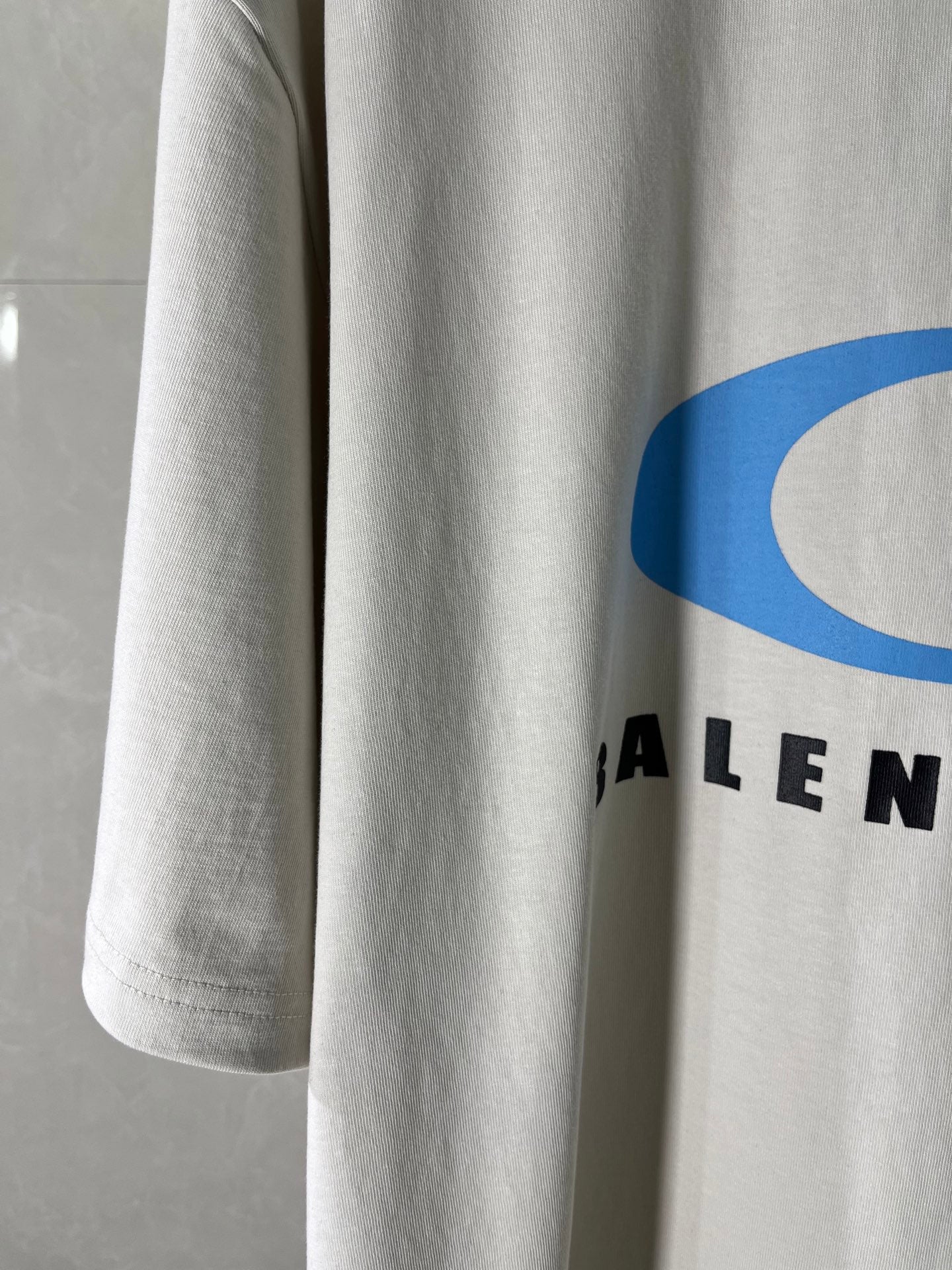 White T-shirt sleeve with partial blue and black BALENCIAGA logo text