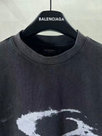 Balenciaga dark T-shirt neckline with “BALENCIAGA” logo on hanger; close-up