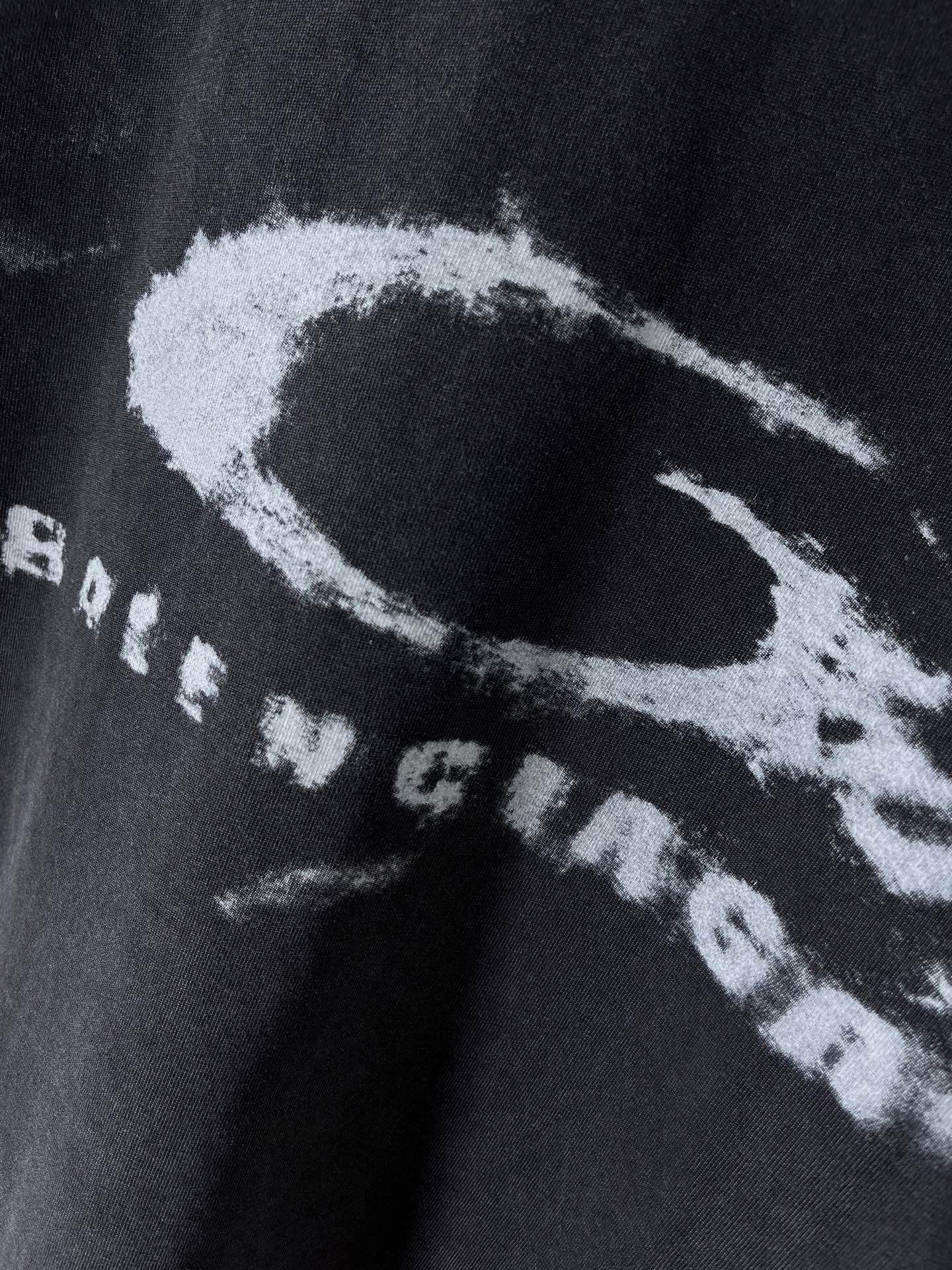 Balenciaga dark T-shirt close-up of large white circular graphic and text