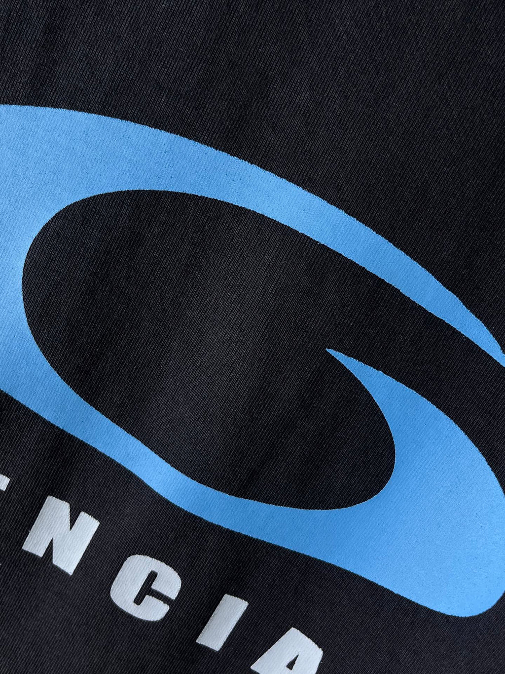 Balenciaga dark T-shirt fabric close-up with blue oval logo