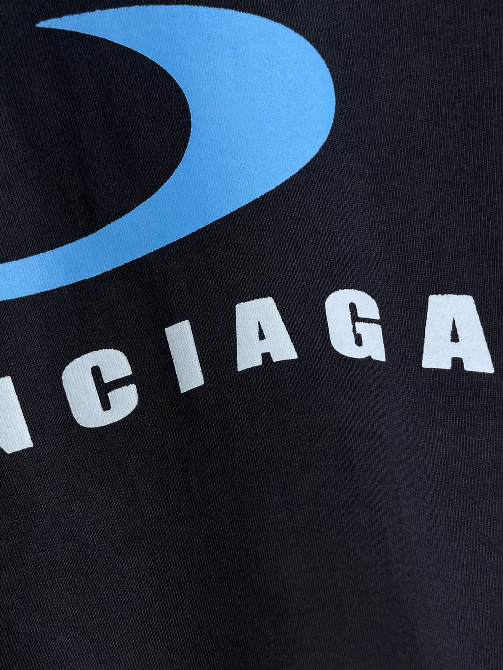 Balenciaga dark T-shirt close-up of blue logo and BALENCIAGA lettering