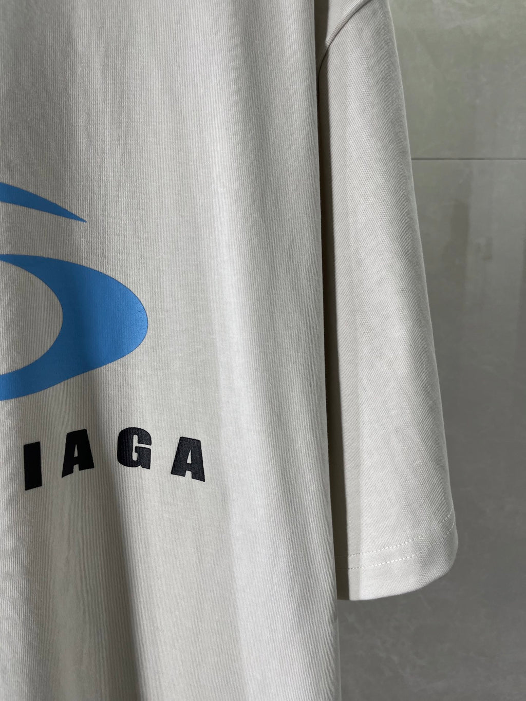 White T-shirt sleeve with partial blue and black BALENCIAGA logo lettering