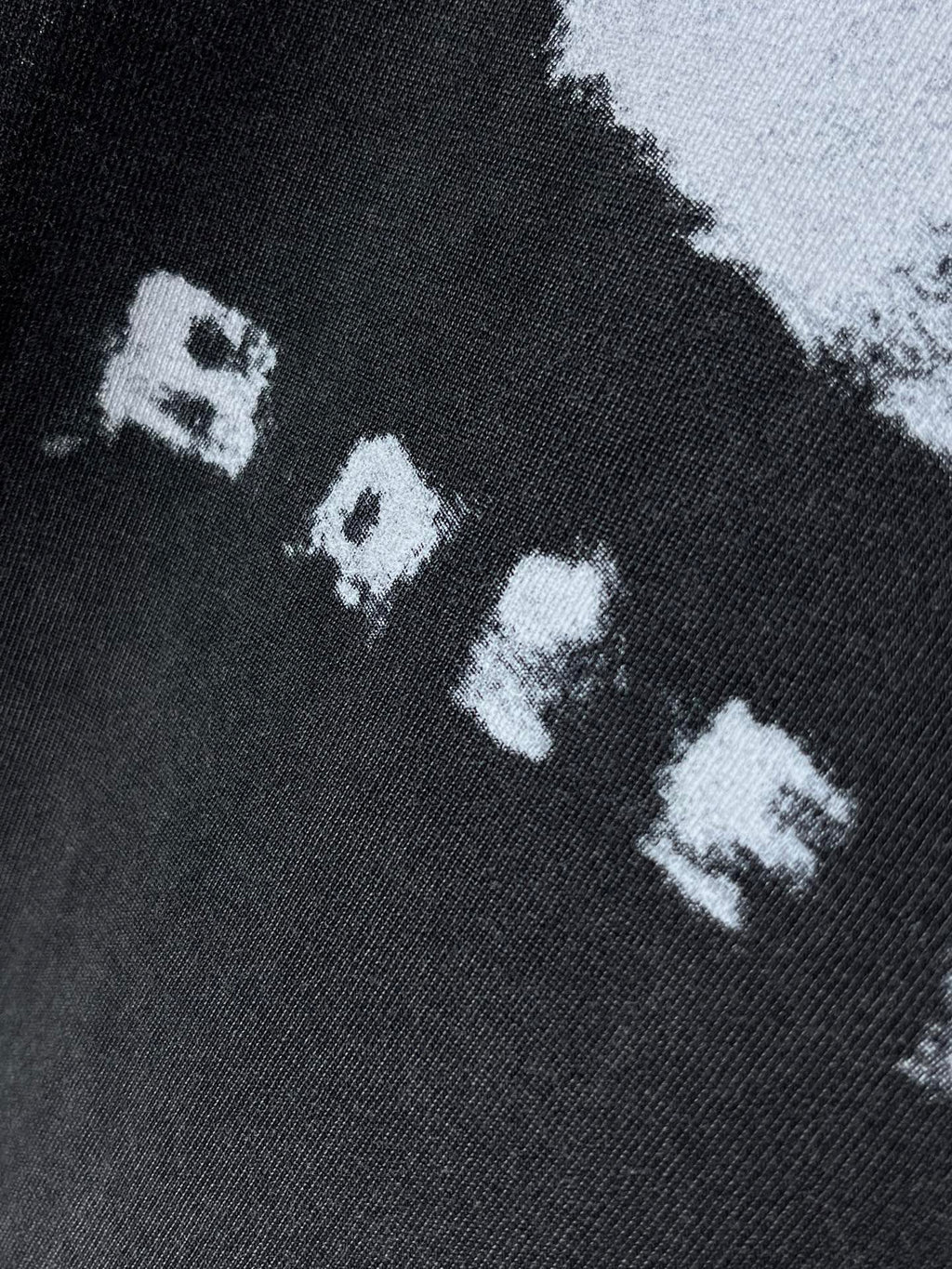 Balenciaga dark T-shirt close-up of white “RAVE” letters in graphic print
