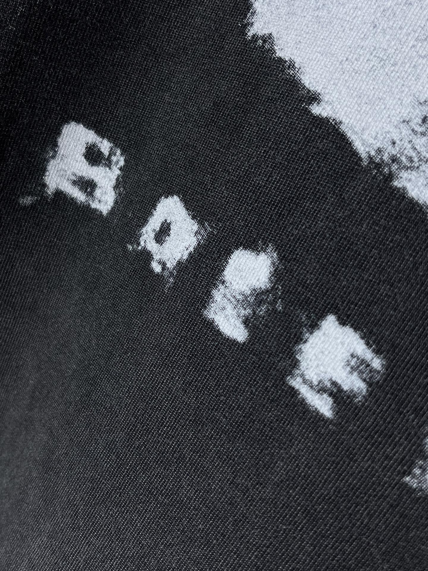 Balenciaga dark T-shirt close-up of white “RAVE” letters in graphic print