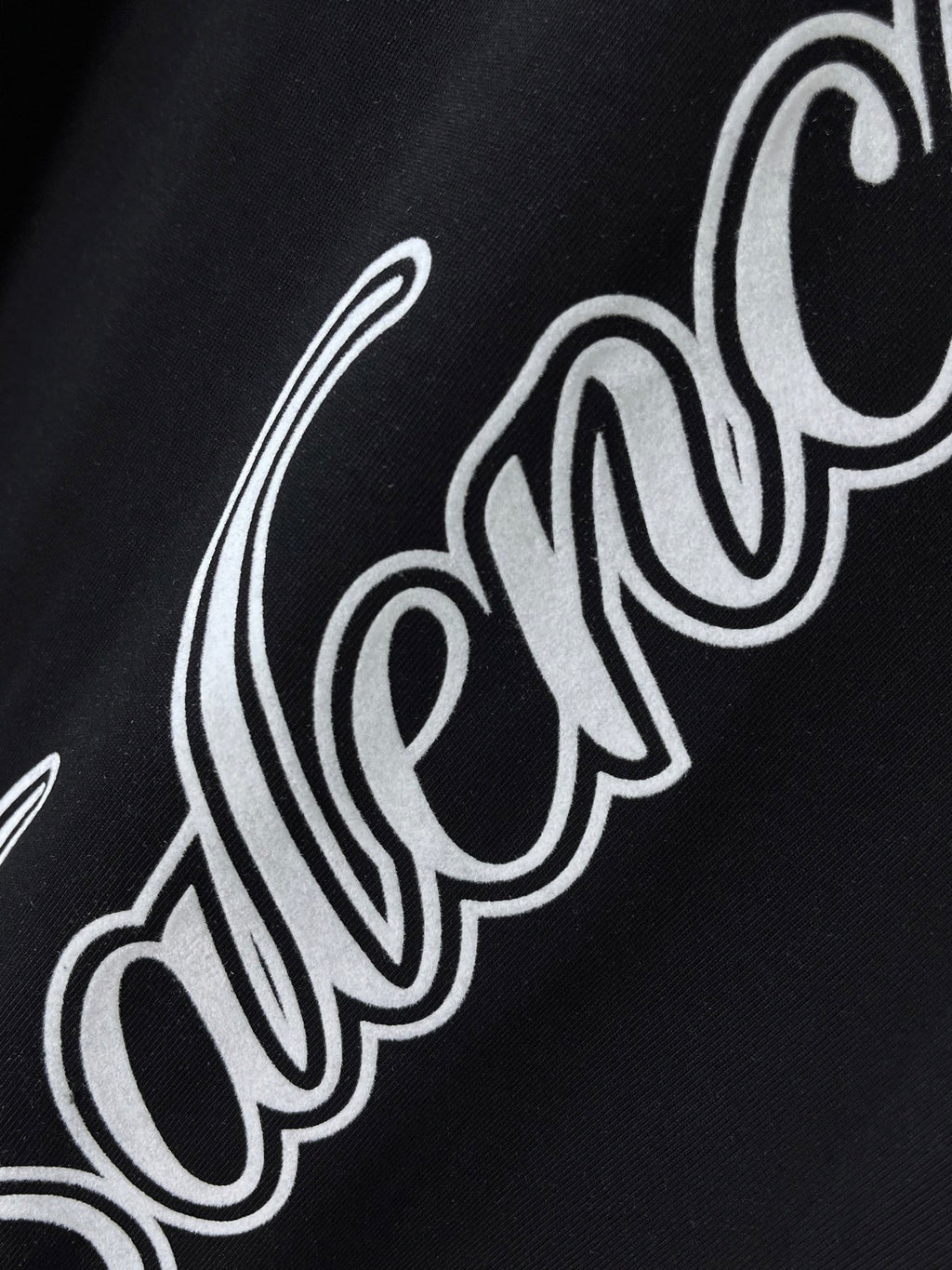 Balenciaga black T-shirt close-up of white script logo across fabric