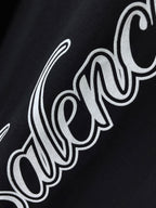 Balenciaga black T-shirt close-up of white script logo across fabric