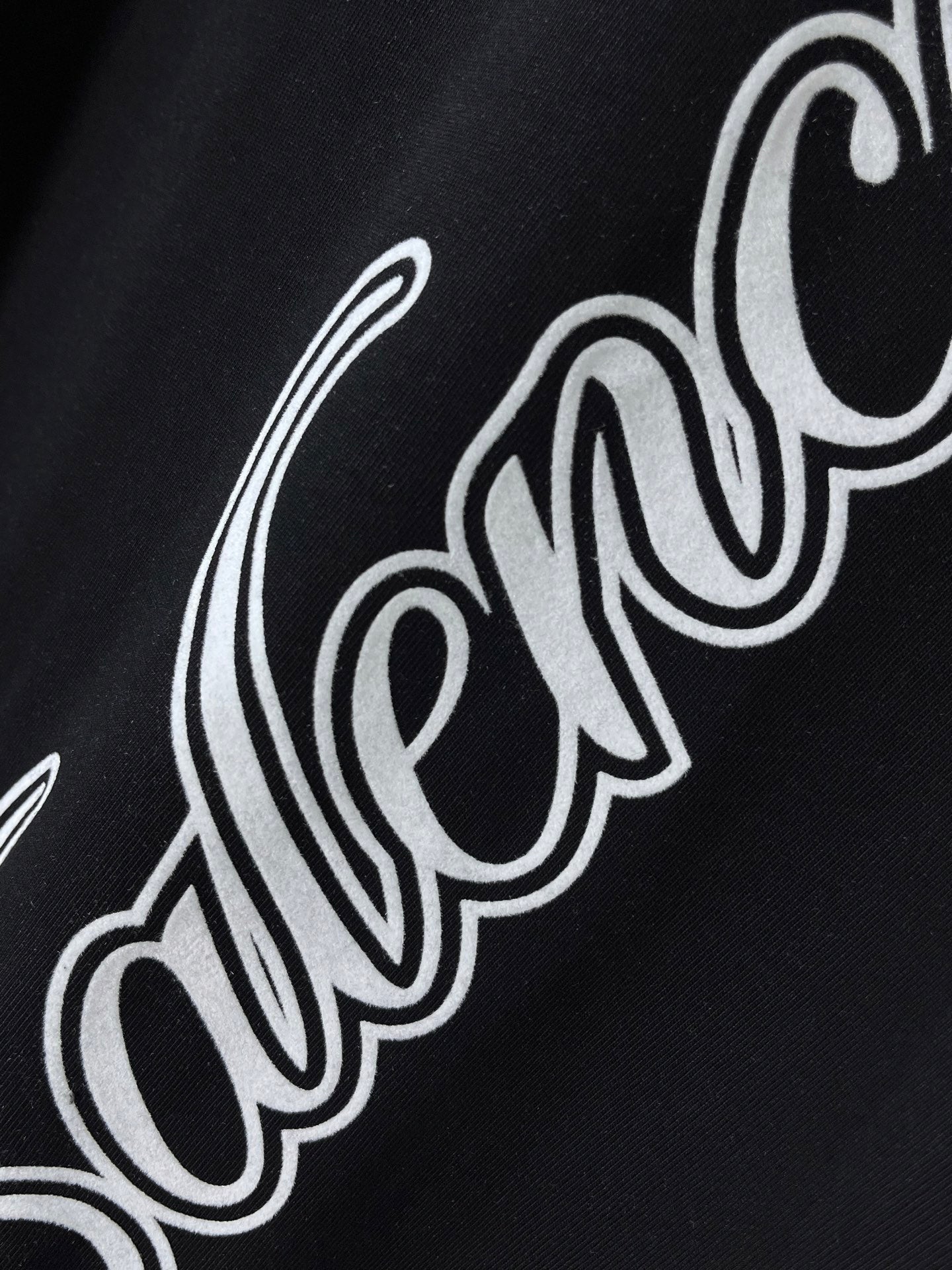 Balenciaga black T-shirt close-up of white script logo across fabric