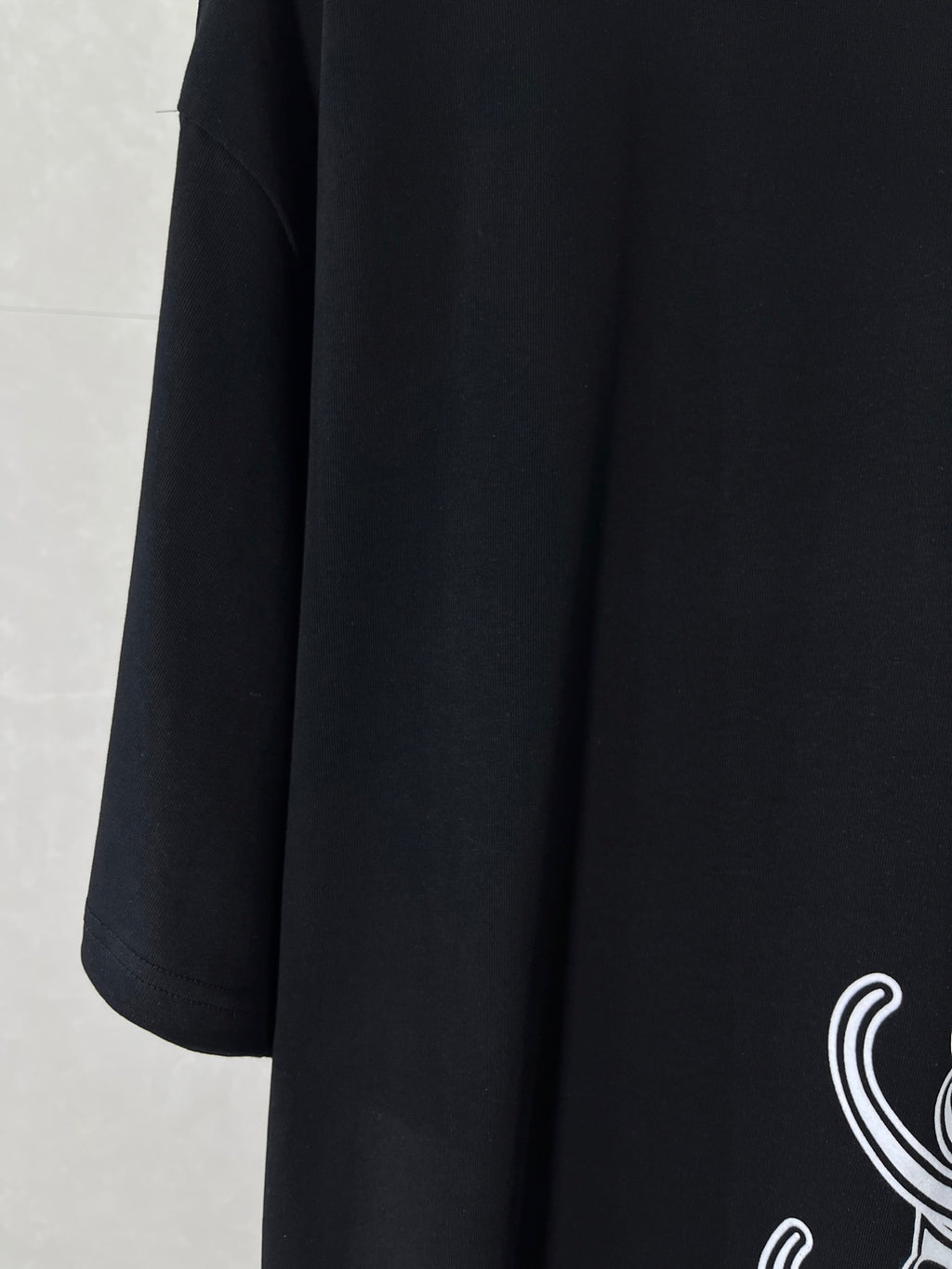 Balenciaga black T-shirt side view with partial white script logo print