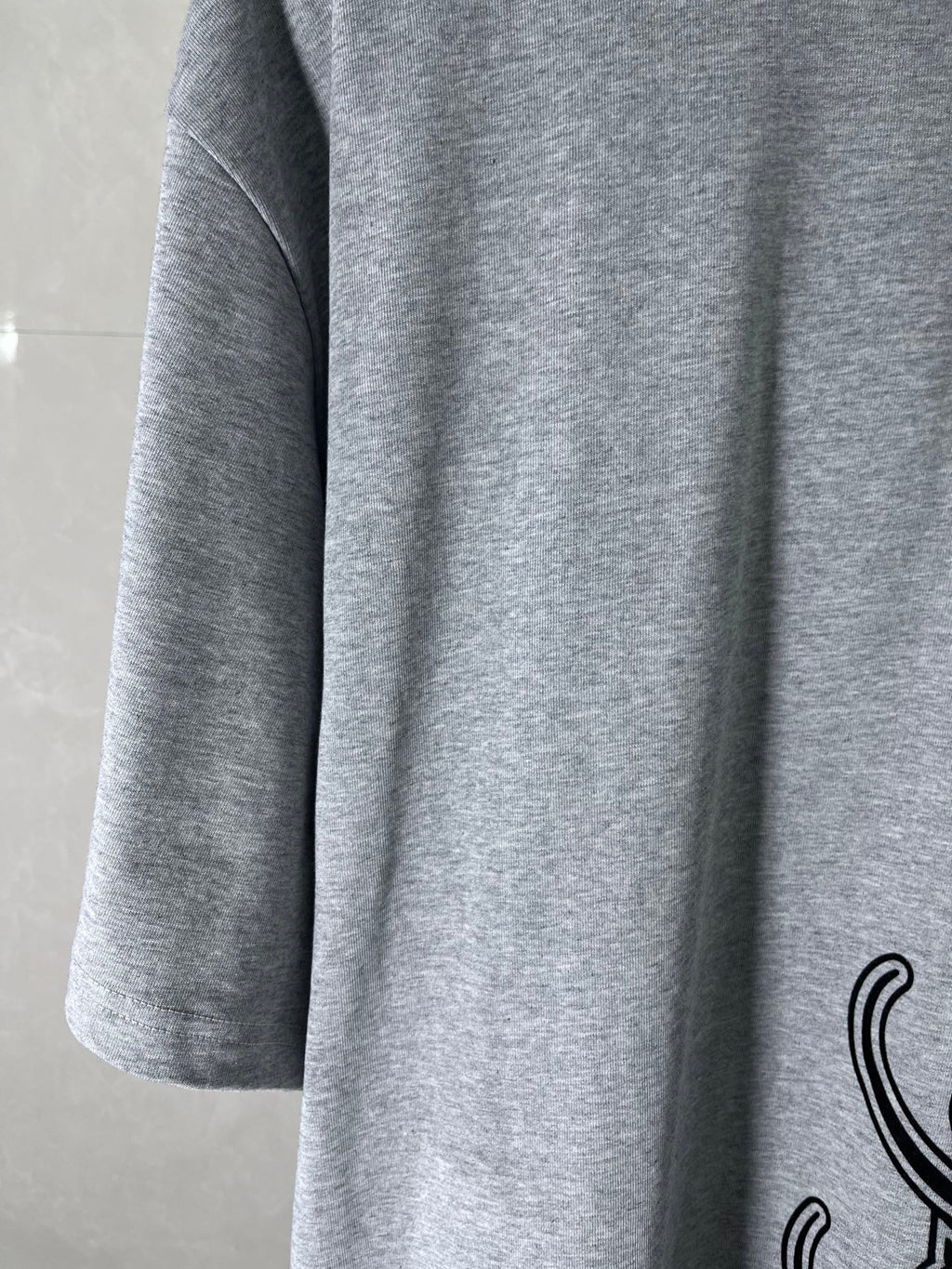 Heather gray T-shirt sleeve and side seam with partial black graphic print
