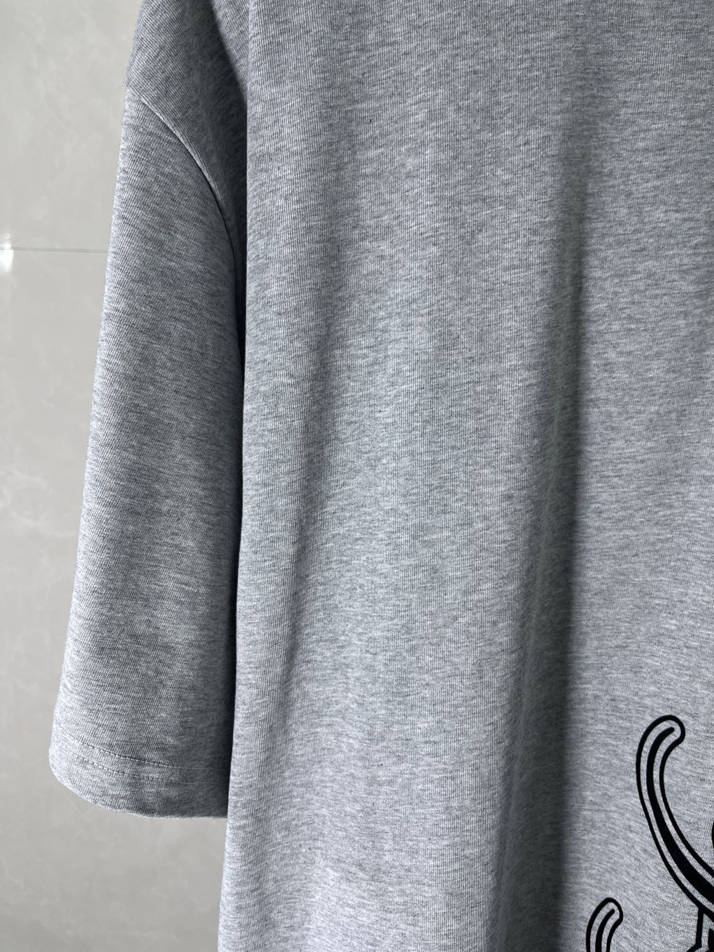 Heather gray T-shirt sleeve and side seam with partial black graphic print