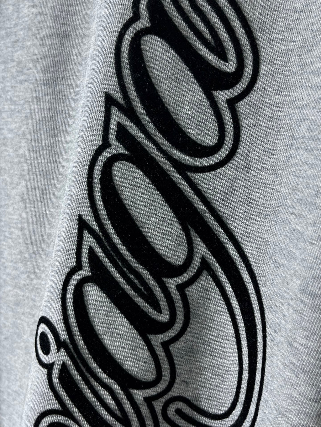 Heather gray T-shirt with oversized black cursive graphic close-up