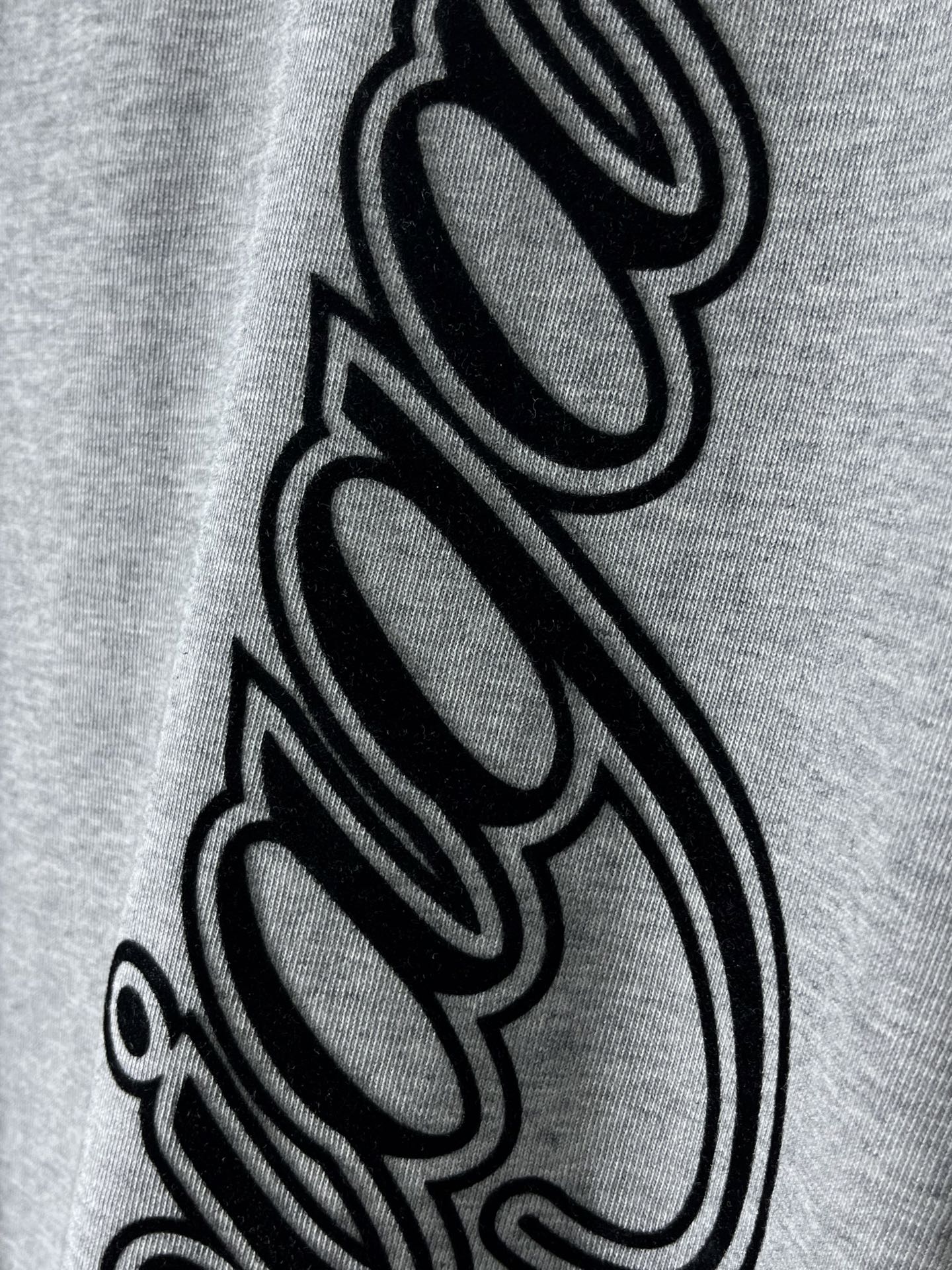 Heather gray T-shirt with oversized black cursive graphic close-up