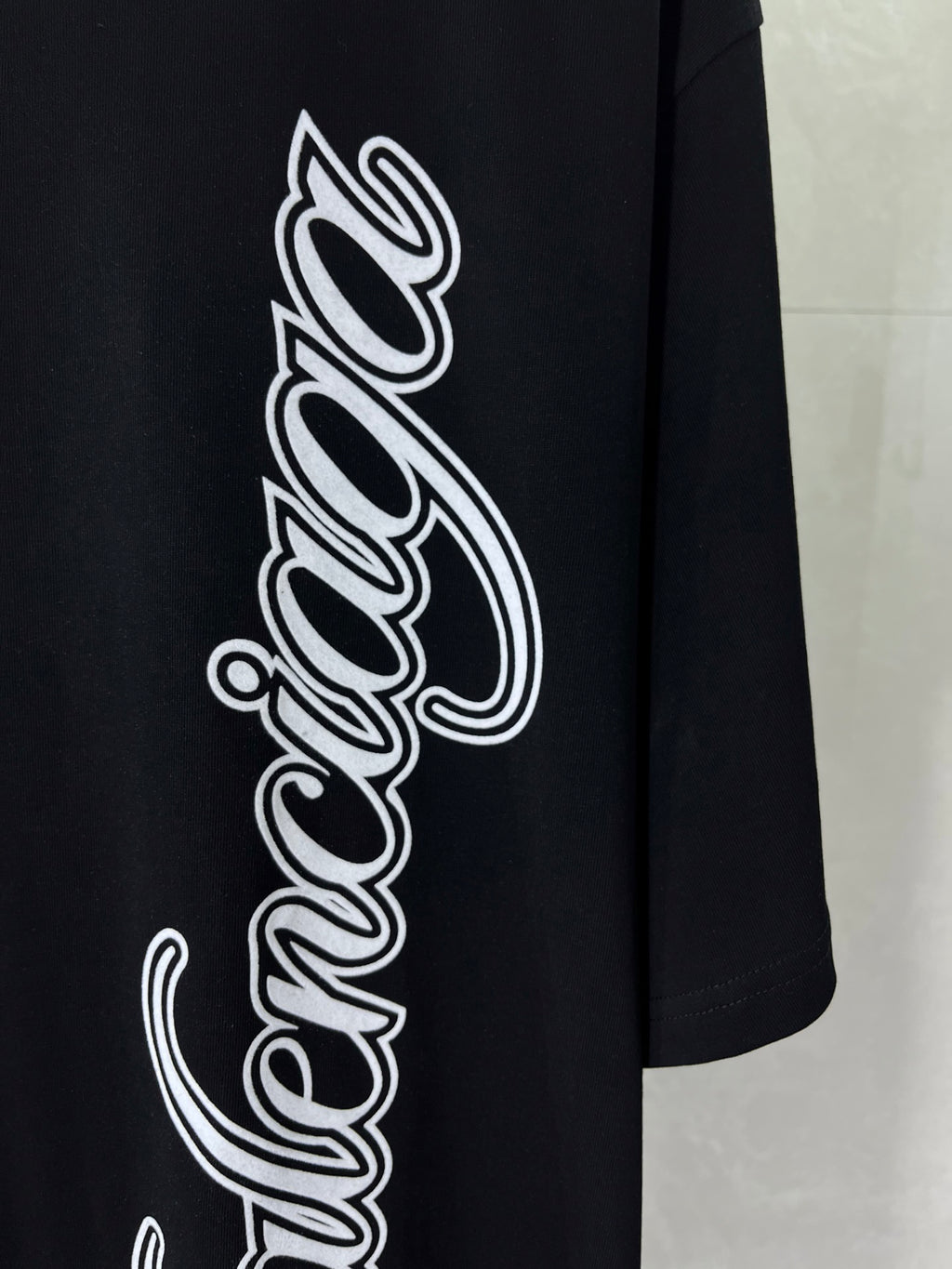 Balenciaga black T-shirt close-up of large white script wordmark graphic