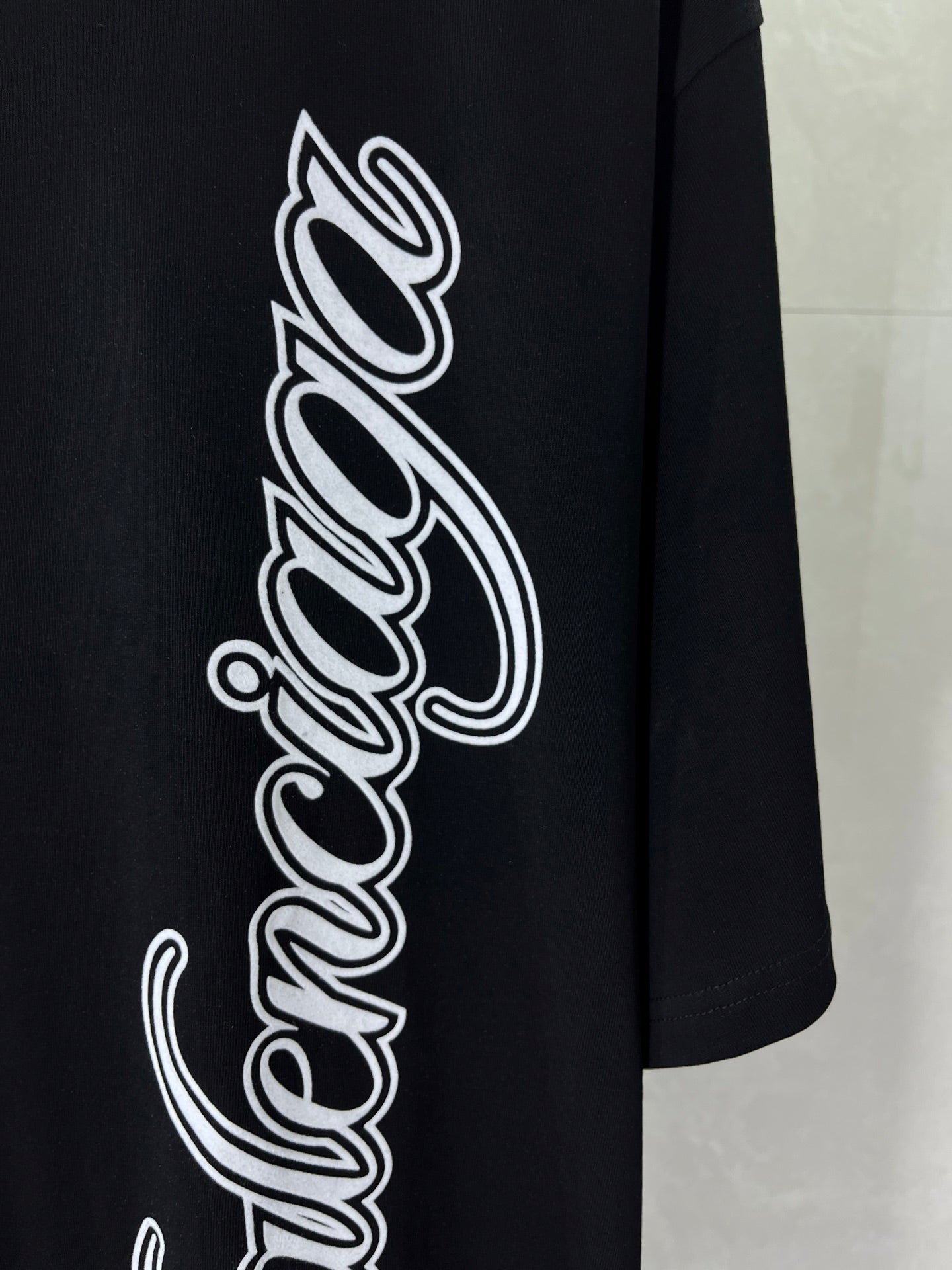 Balenciaga black T-shirt close-up of large white script wordmark graphic