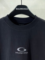 Dark T-shirt neckline with BALENCIAGA logo patch at center chest