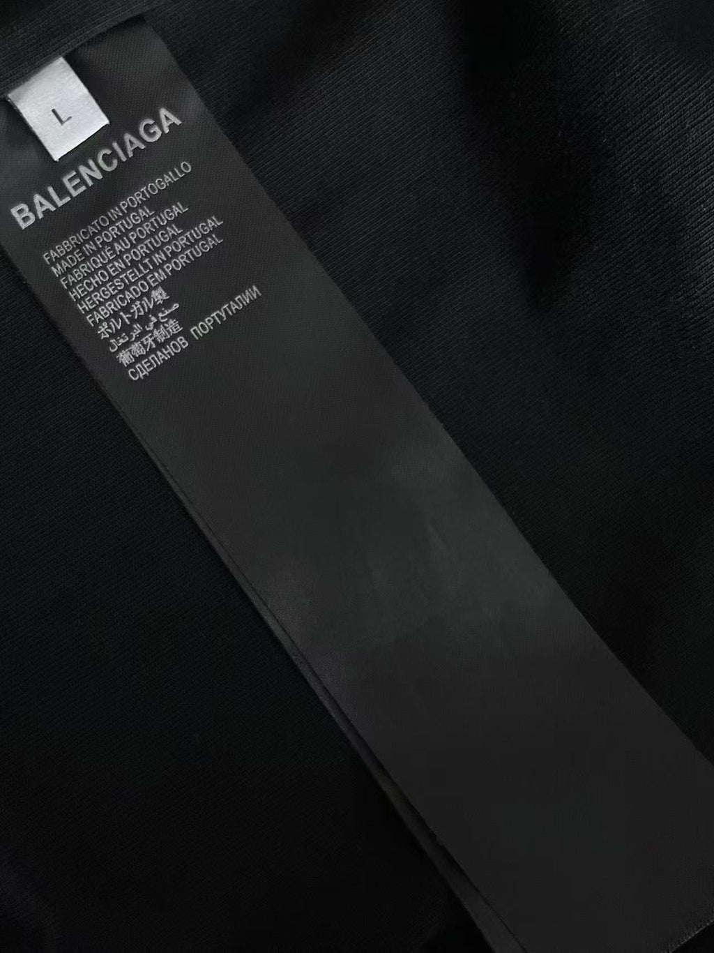Black fabric care label on T-shirt tag with text and logo
