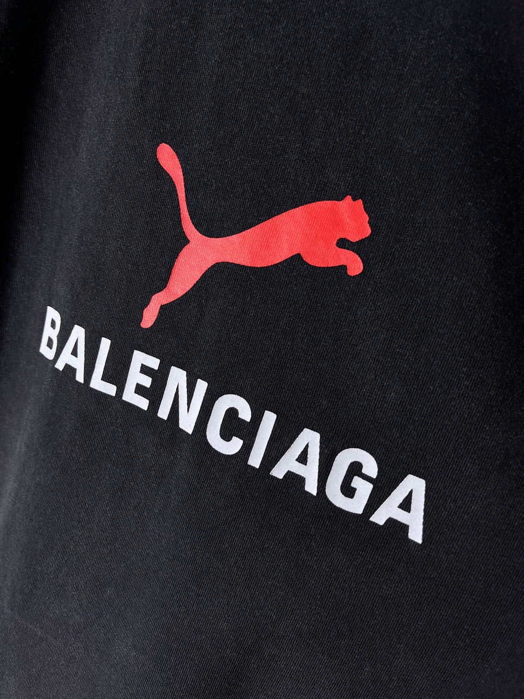 Dark navy T-shirt close-up of red puma-style logo and BALENCIAGA text