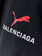 Dark navy T-shirt close-up of red puma-style logo and BALENCIAGA text