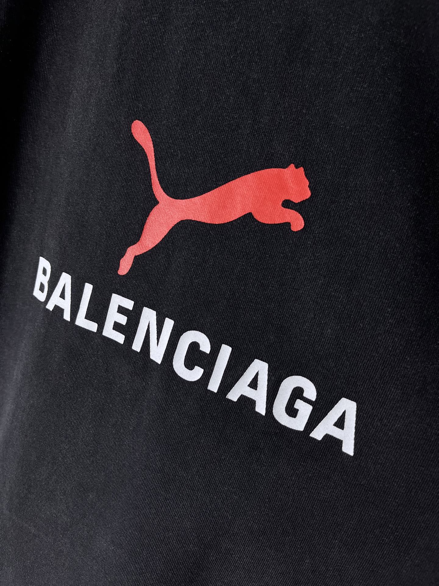 Dark navy T-shirt close-up of red puma-style logo and BALENCIAGA text