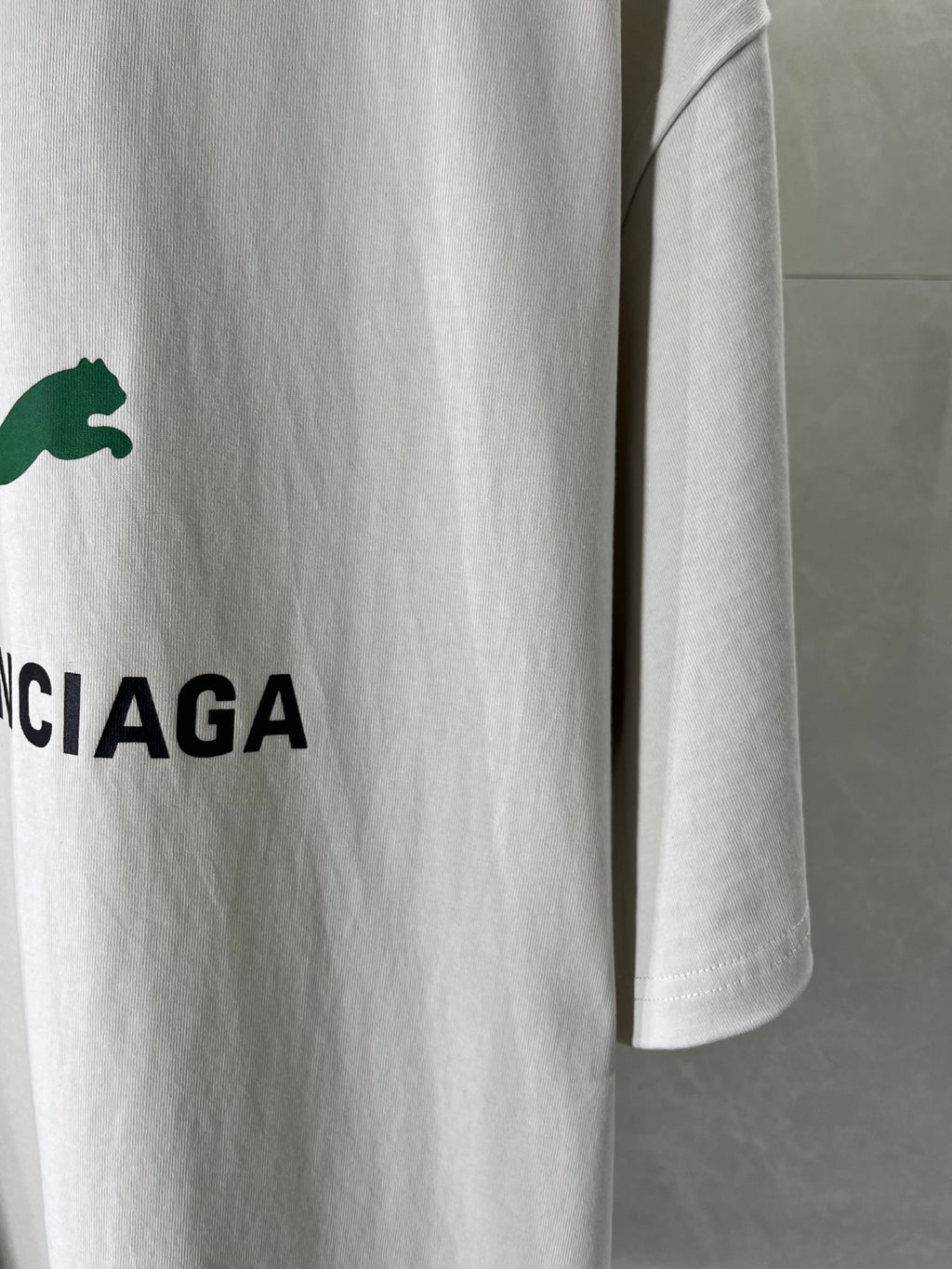 White Balenciaga T-shirt sleeve detail with green puma logo and CIAGA letters