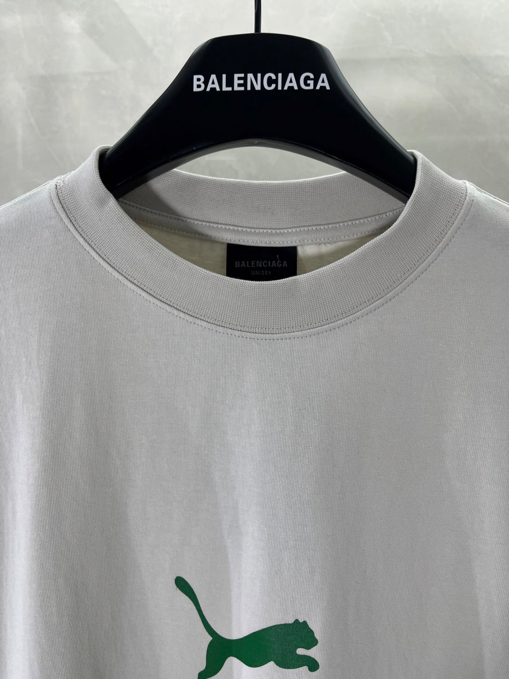 White Balenciaga T-shirt close-up: crew neck and green puma logo detail