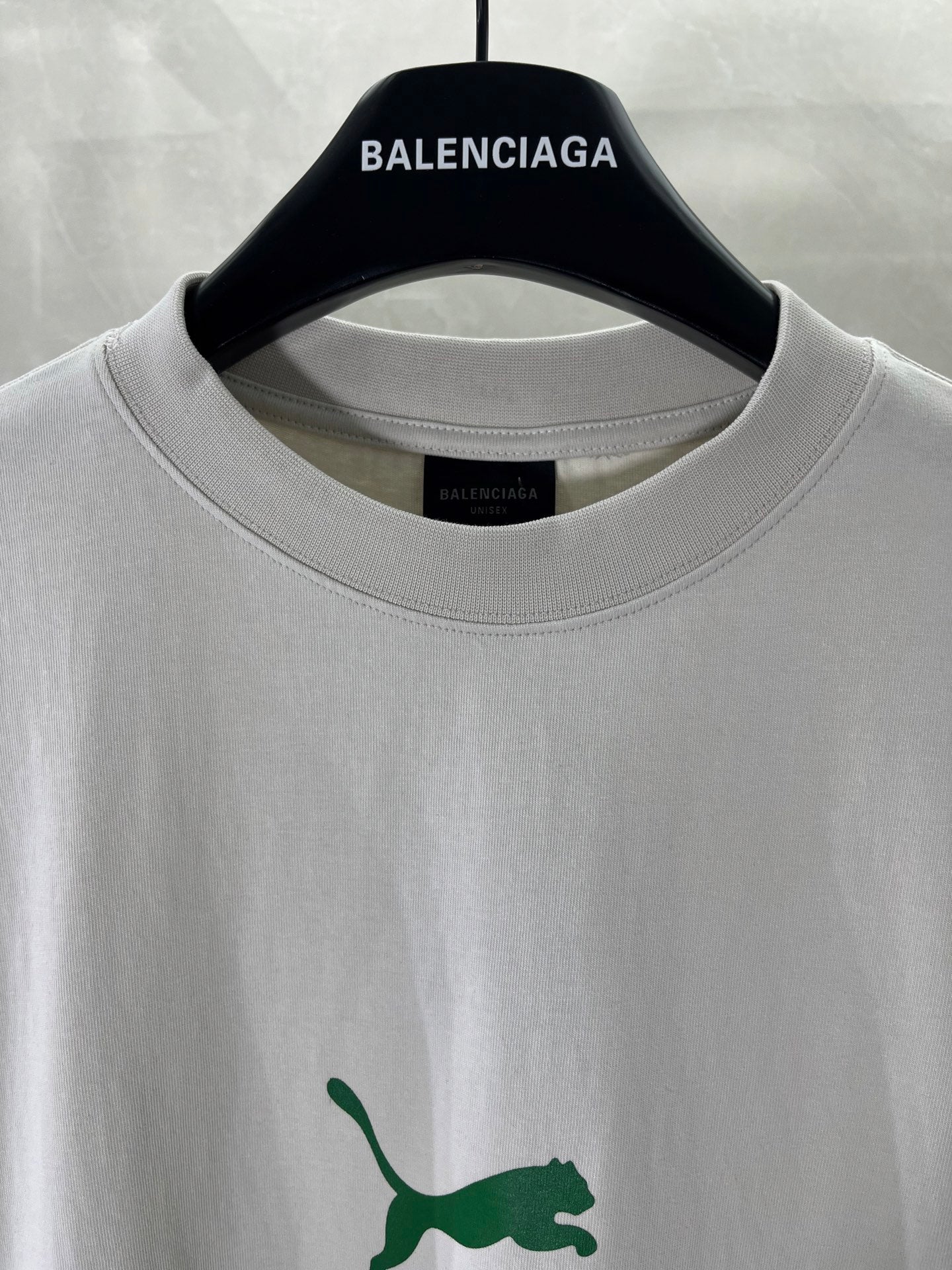 White Balenciaga T-shirt close-up: crew neck and green puma logo detail