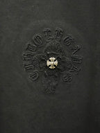 Black fabric T-shirt with detailed embroidered cross emblem and gold center detail.