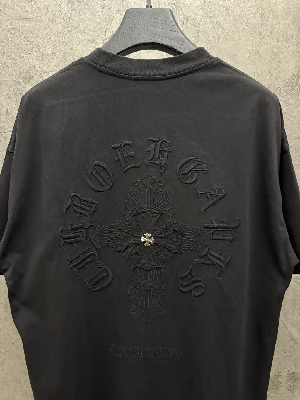 Black short-sleeve T-shirt with large back cross emblem embroidery and crew neck.