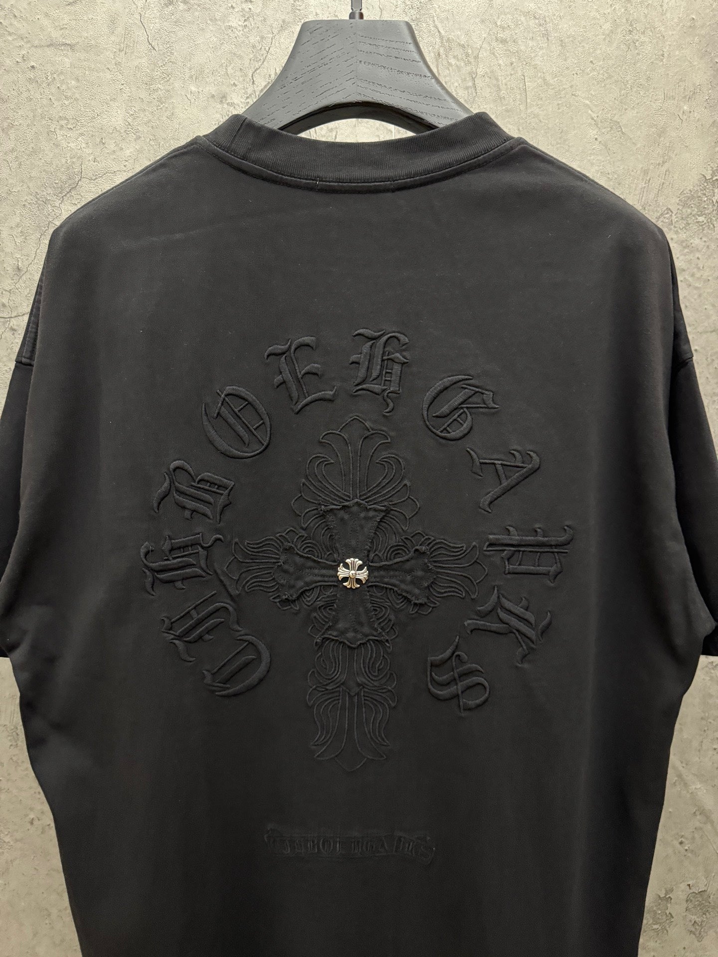 Black short-sleeve T-shirt with large back cross emblem embroidery and crew neck.