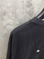 Black T-shirt crew neck and sleeve seam with small chest emblem detail.