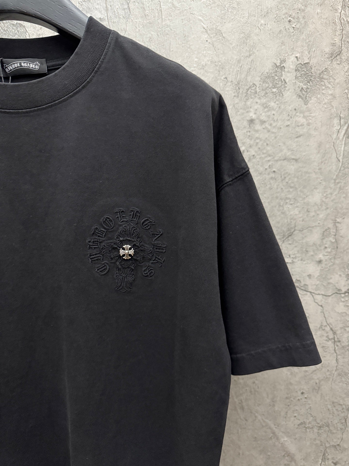 Black short-sleeve T-shirt with circular chest emblem and crew neck.