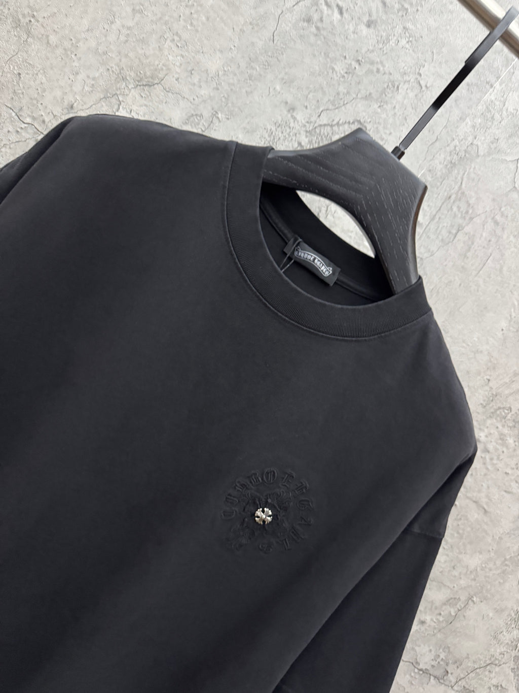 Black crew-neck T-shirt with embroidered chest emblem and interior neck label.