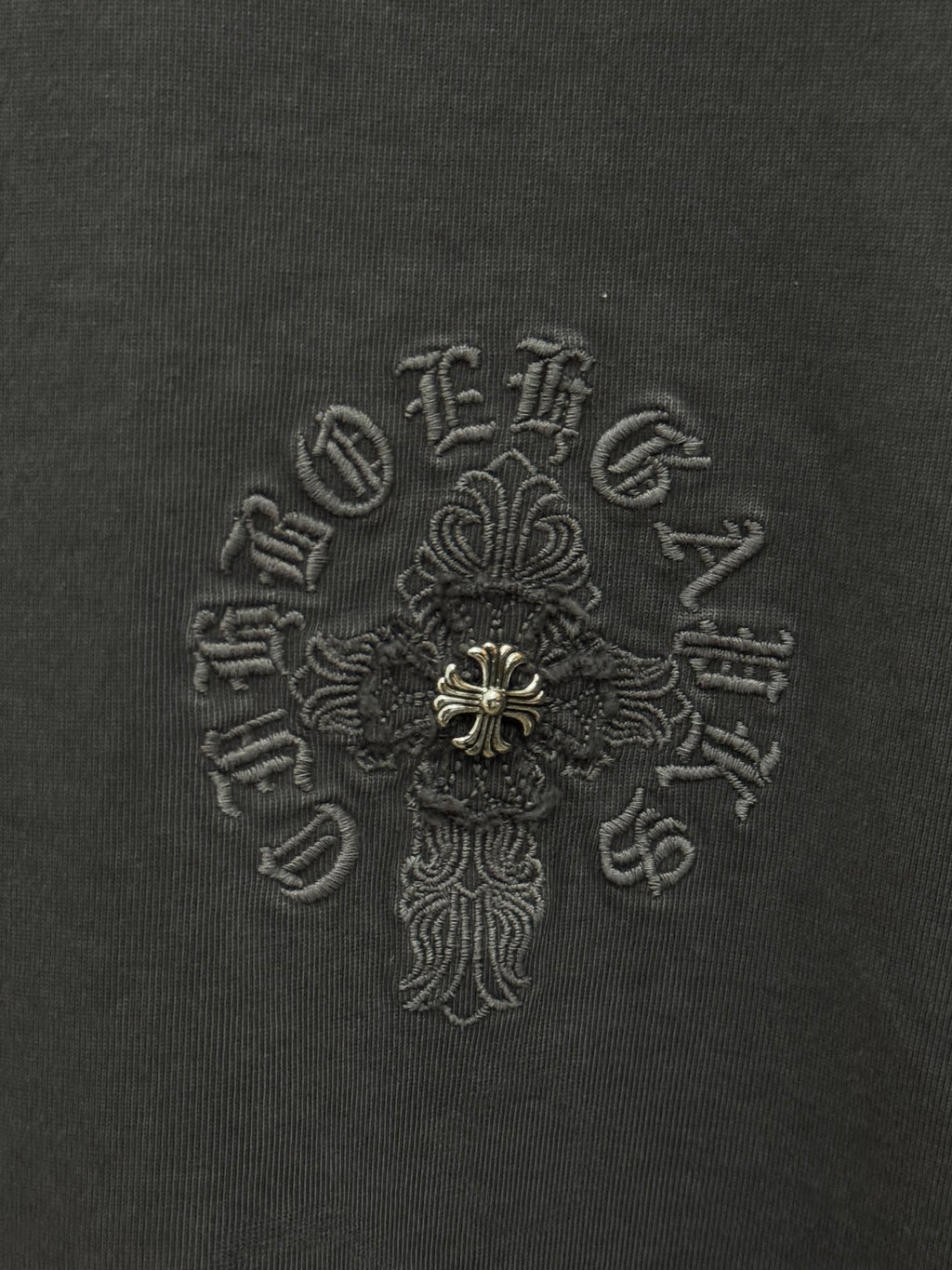 Dark gray T-shirt fabric with detailed embroidered cross emblem in center