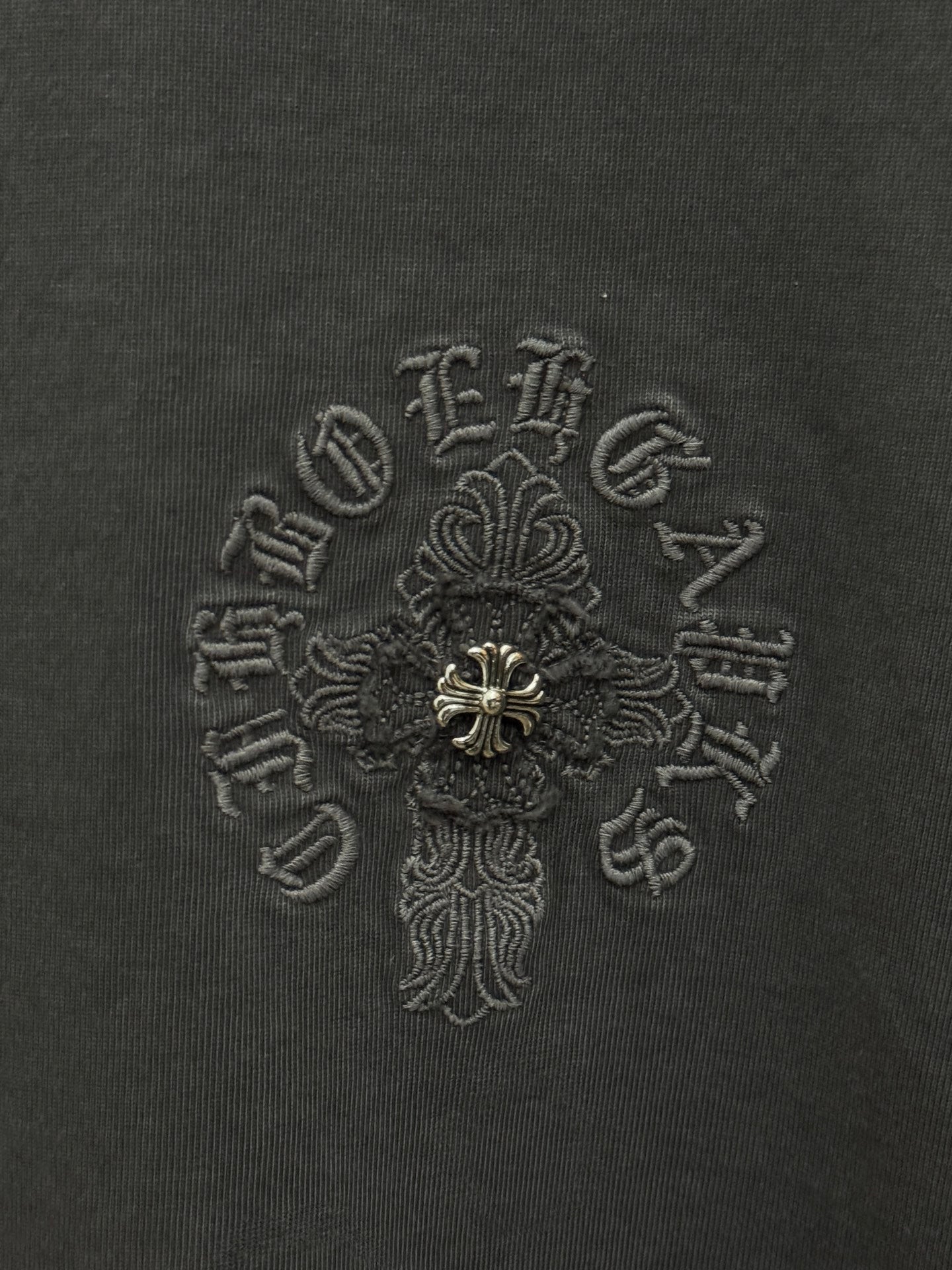 Dark gray T-shirt fabric with detailed embroidered cross emblem in center