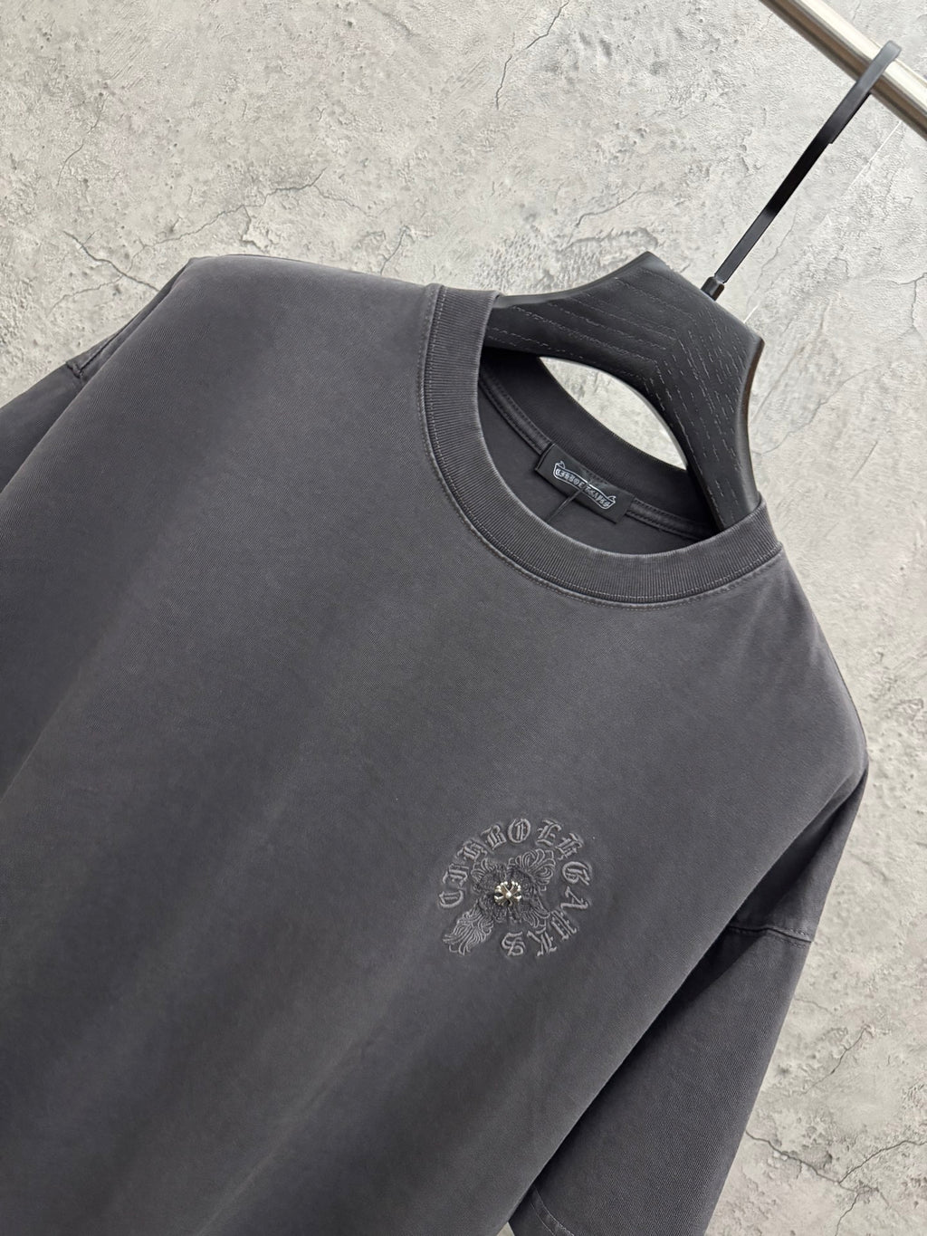 Dark gray crewneck T-shirt neckline with small embroidered chest logo